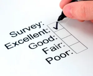 A hand ticking the top box on a survey rating scale from Excellent to Poor