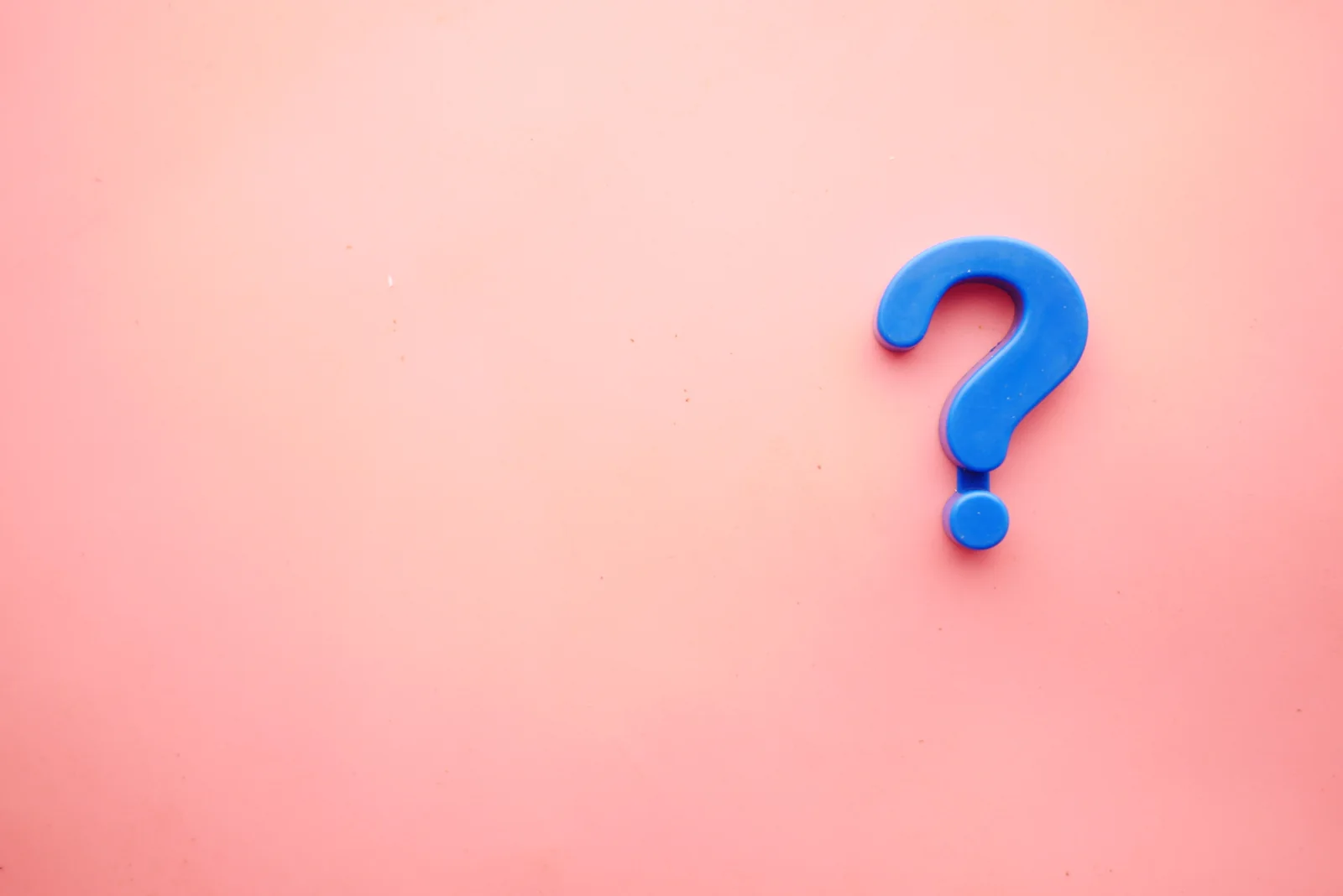 Blue plastic question mark on a pink background