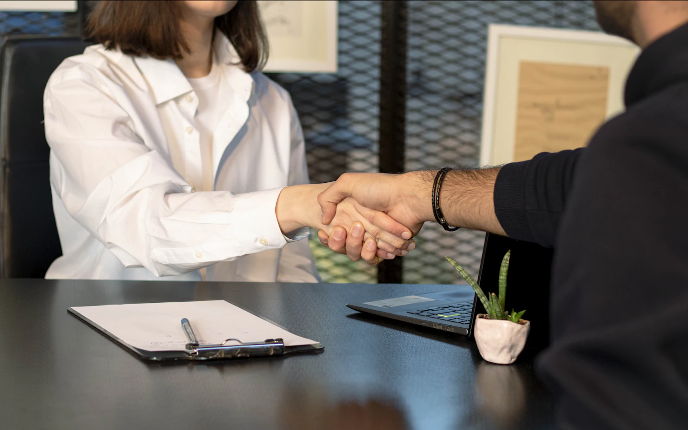 Two professionals shaking hands across a desk